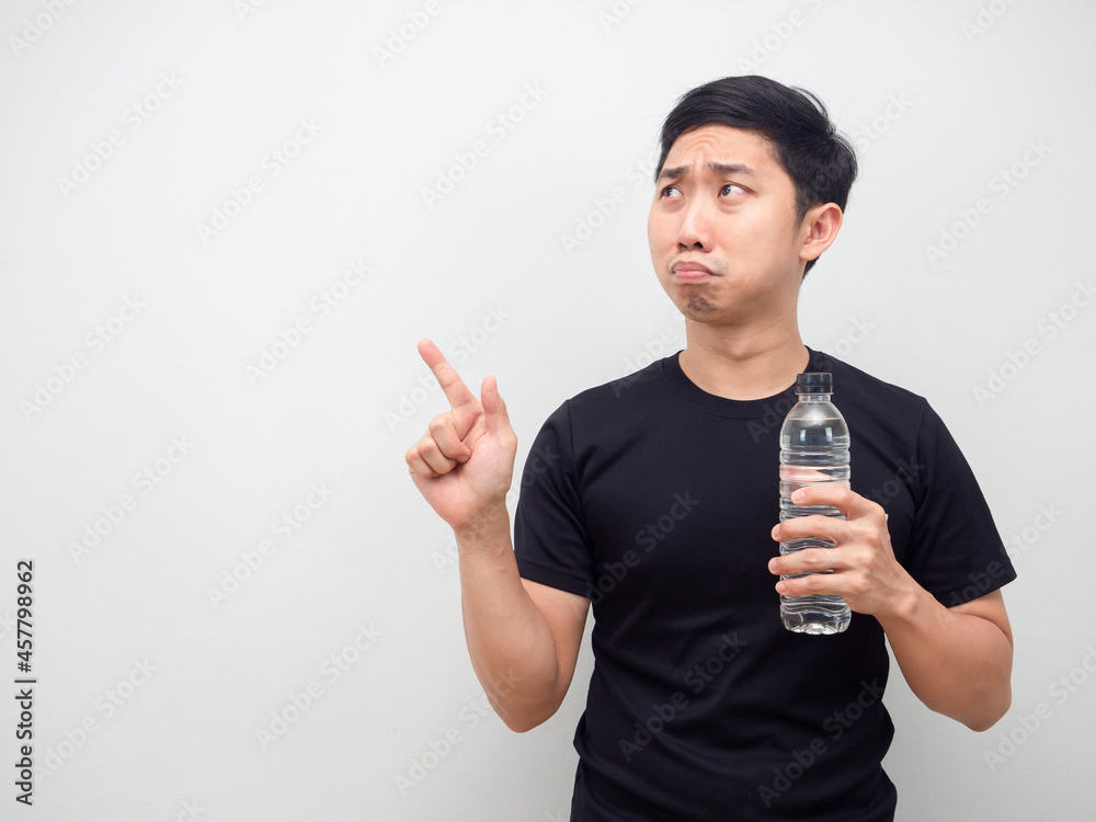 Asian man holding water bottle and feeling sad emotion point finger at copy space Asian man holding water bottle and feeling sad emotion point finger at copy space