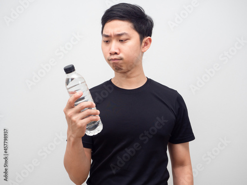 Asian man looking at water bottle in his hand and feeling hesitage on white background