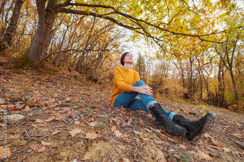 Woman hiking looking at scenic view of autumn foliage mountain landscape. Outdoor adventure travel lady sitting relaxing in nature in autumn season. Woman hiking looking at scenic view of autumn foliage mountain landscape. Outdoor adventure travel lady sitting relaxing in nature in autumn season.