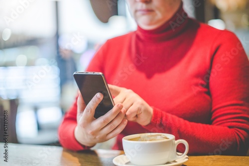 A woman writes in her smartphone while sitting in a cafe 