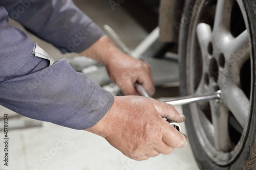 We got a flat tire - the man hands screws the nut on the alloy wheel with a cross wrench close up