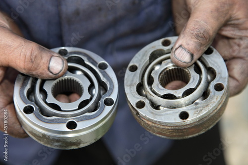 Two used CV joint tripods close up in serviceman dirty hands, CV joints replacement car repair service