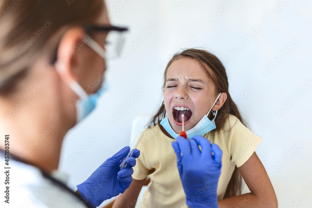 Nurse performing a mouth swab test on a little child. Girl going through PCR testing due to COVID-19 pandemic. Female doctor using cotton swab while PCR testing small girl