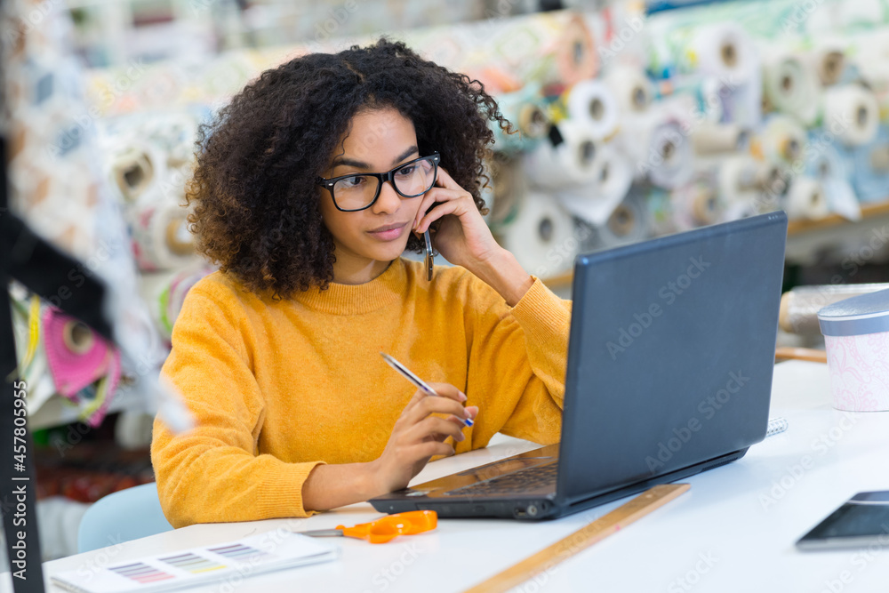 pensive female fashion designer reading data on laptop screen pensive female fashion designer reading data on laptop screen