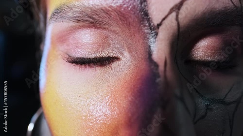 model in makeup on a dark background closes her eyes holiday Halloween macro slow motion