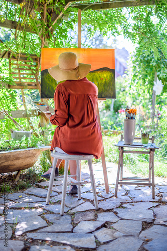 Young female artist working on her art canvas painting outdoors in her garden Fototapete