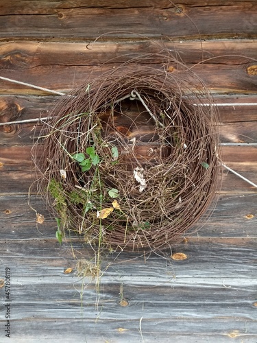 A wreath of rusty wire with green plants hanging on an old wooden wall