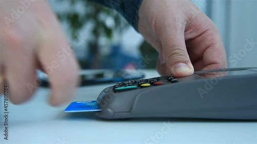 Hand Inserts Credit Card Into Terminal And Enters Password For Payment. Electronic Money And Shopping Concept.  Slow Motion Effect. Close Up