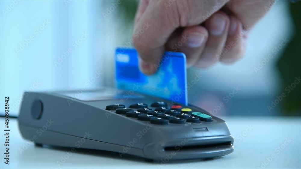 Hand Inserts Credit Card Into Terminal And Enters Password For Payment. Electronic Money And Shopping Concept. Slow Motion Effect. Close Up Hand Inserts Credit Card Into Terminal And Enters Password For Payment. Electronic Money And Shopping Concept. Slow Motion Effect. Close Up
