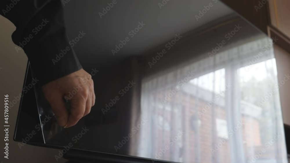  After unpacking man's hand removing protective plastic film from brand new television set oled screen applied in the factory.