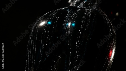 close-up of a swaying female ass in a black latex suit and streaked with white liquid on a dark background photo