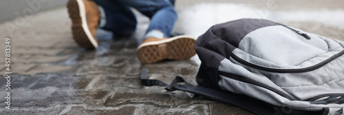 Man with backpack felling on slippery sidewalk in winter closeup