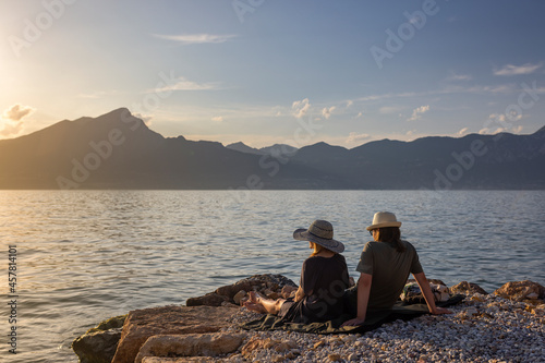 Italy - Lake Garda in the town of Torri del Benaco. A sunset, a romantic couple by the water, in the distance you can see the mountain peaks.
