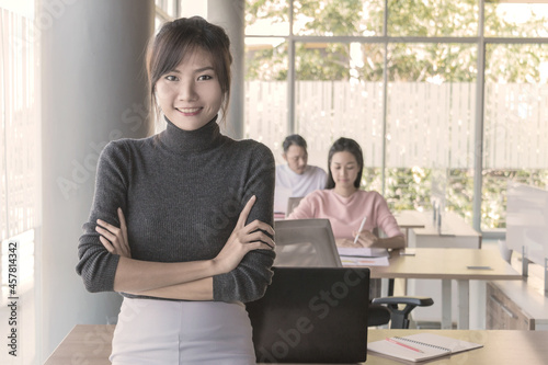 Portrait of asian business woman who standing in feeling happy at the office with daylight from window and blur garden background.