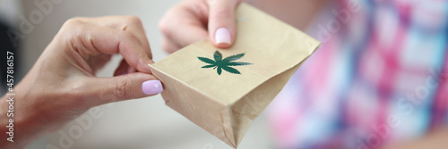 Woman giving paper bag of marijuana closeup photo