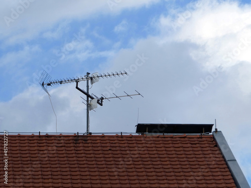 Obraz na plátně TV satellite dish and antennas on a house roof against cloudy blue sky