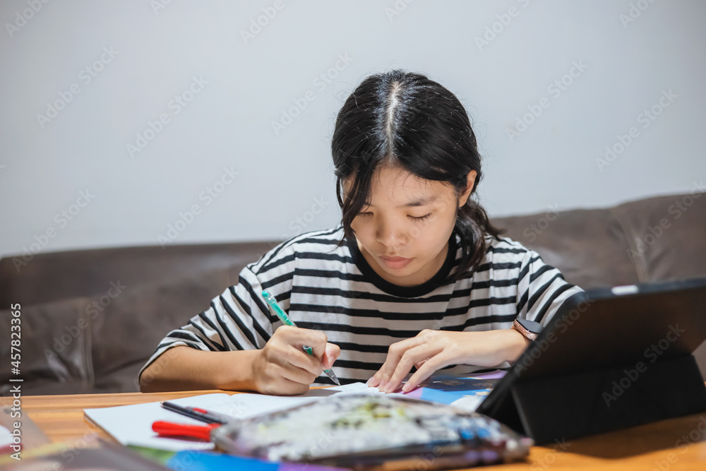 Students use pens to write notebooks and tablets on their desks for online learning. Students use pens to write notebooks and tablets on their desks for online learning.