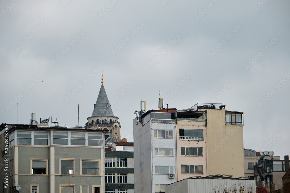 Famous galata tower of istanbul taken photo from istanbul bosphorus. Galata tower during overcast sky and rainy day with single seagull flying over the tower.