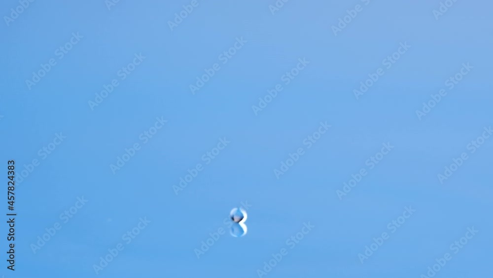 Close up water drop splash with ripple and round of water falling in glass blue colored background, side view in slow motion. Close up water drop splash with ripple and round of water falling in glass blue colored background, side view in slow motion.