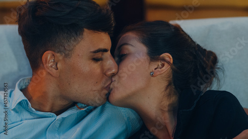 Fotografi Attractive cheerful young caucasian couple kissing romantic moment while watching film in movie theater