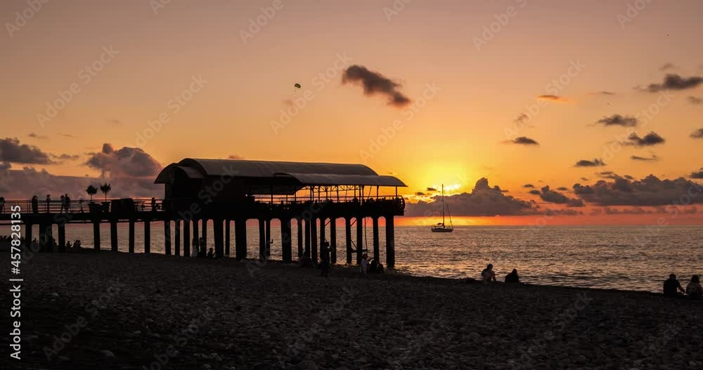 time lapse of silhouette of gazebo on stilts against the backdrop of sunset on ocean or sea with bustling people time lapse of silhouette of gazebo on stilts against the backdrop of sunset on ocean or sea with bustling people
