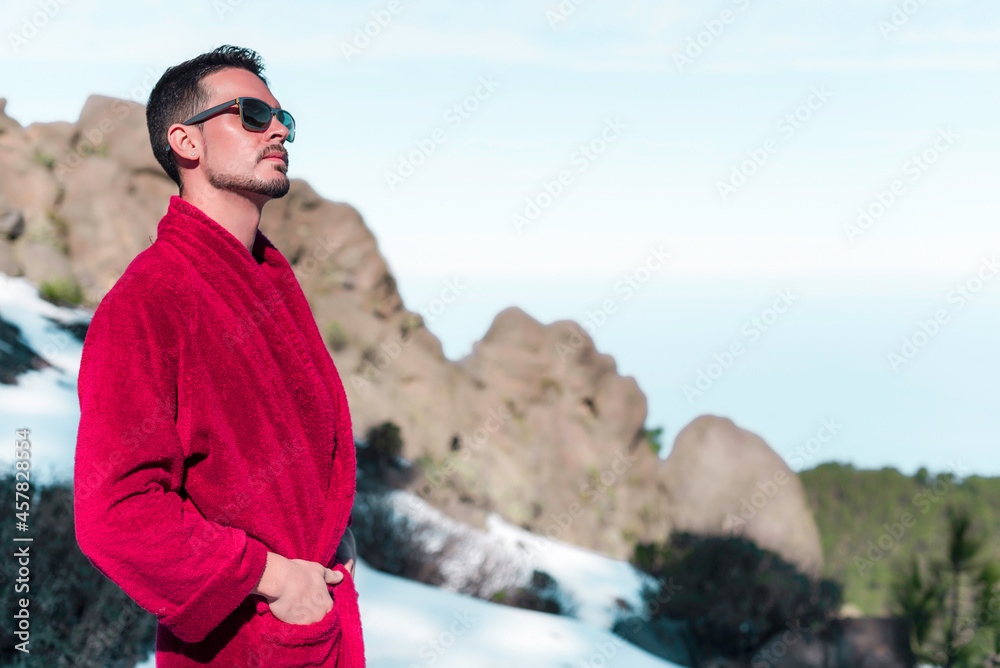 Young man in red long bathrobe is enjoying the snowy sunny day on mauntain top Young man in red long bathrobe is enjoying the snowy sunny day on mauntain top