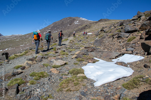 hikers going up to Mulhacen through a mountainous area with a bit of snow photo