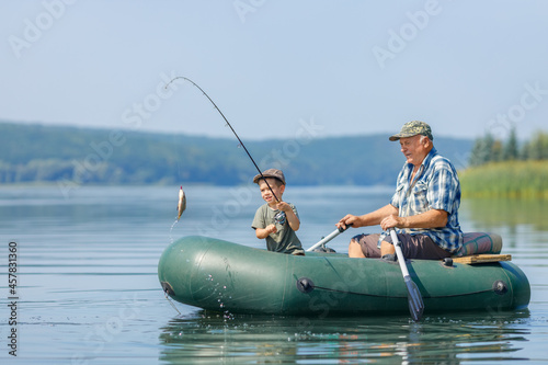 Foto grandfather with grandson together fishing from inflatable boat