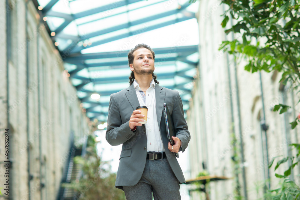 A young successful businessman is walking down the street. Man in a casual wear. Business, freelance and remote work. A young successful businessman is walking down the street. Man in a casual wear. Business, freelance and remote work.