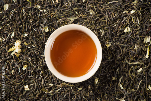 a cup of jasmine scented tea on dried tea leaves background