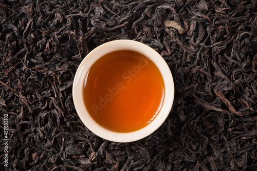 a cup of black tea on dried tea leaves background