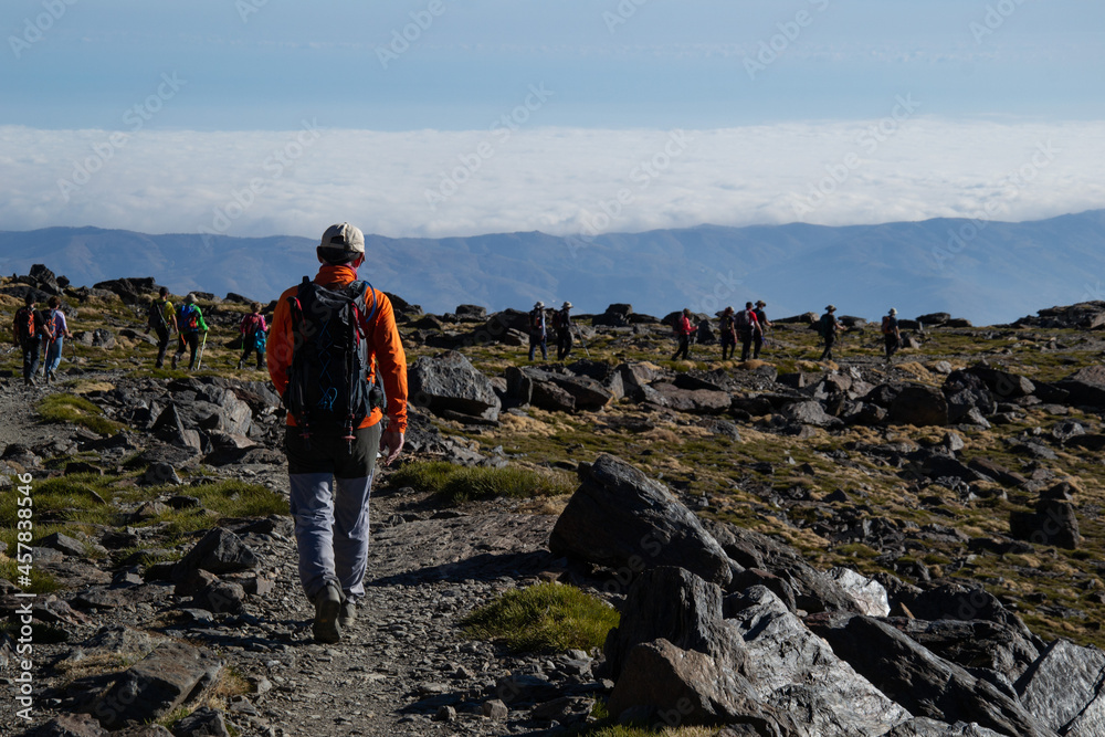 a hiker in the foreground surrounded by rocks and more people in the background with a sea of low clouds in the Sierra Nevada a hiker in the foreground surrounded by rocks and more people in the background with a sea of low clouds in the Sierra Nevada