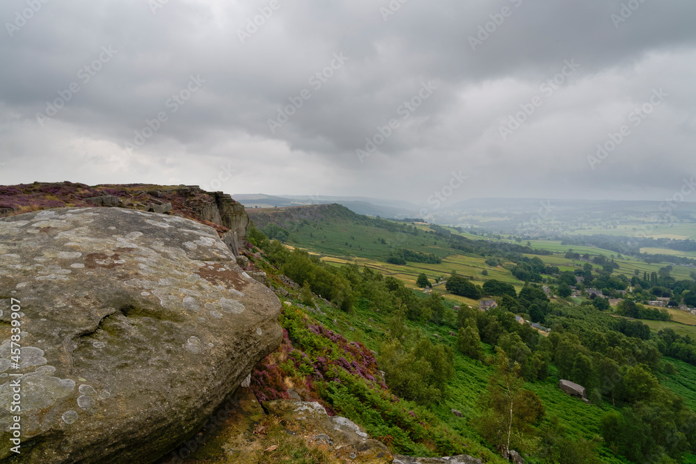 On a summer morning unseasonably dark grey skies and mist over Curbar Edge the Derbyshire Peak District.