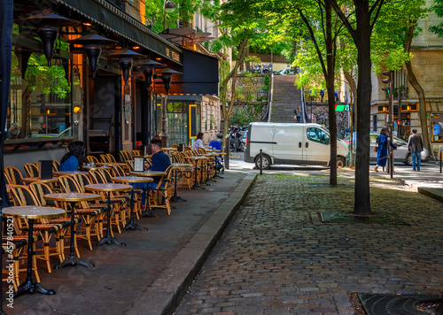 Cozy street with tables of cafe in quarter Montmartre in Paris, France. Architecture and landmarks of Paris. Postcard of Paris
