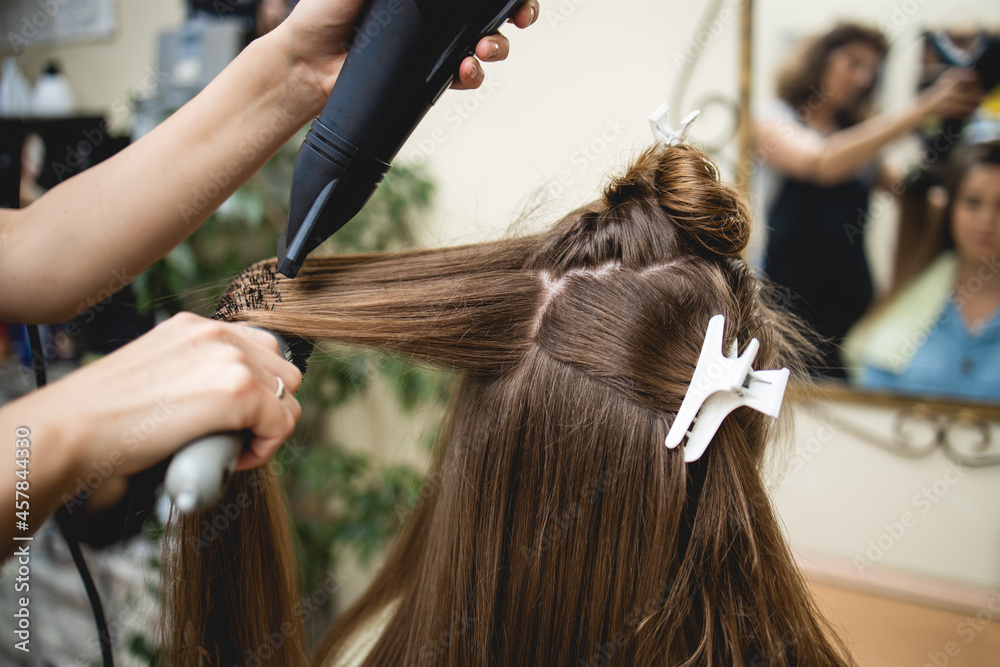 Naklejka premium A woman customer getting a new hairstyle by female hairdresser.Close up photo.