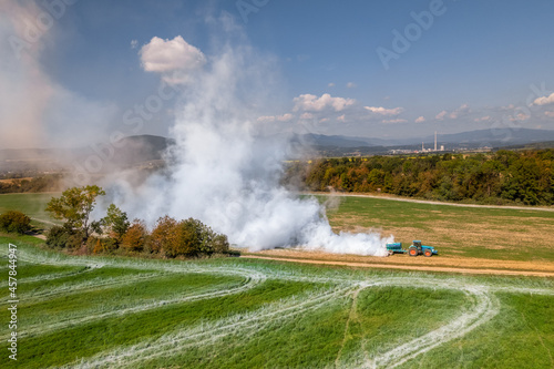 Aerial view of a tractor spreading lime on agricultural fields to improve soil quality after the autumn harvest. The use of lime powder to neutralize the acidity of the soil. photo