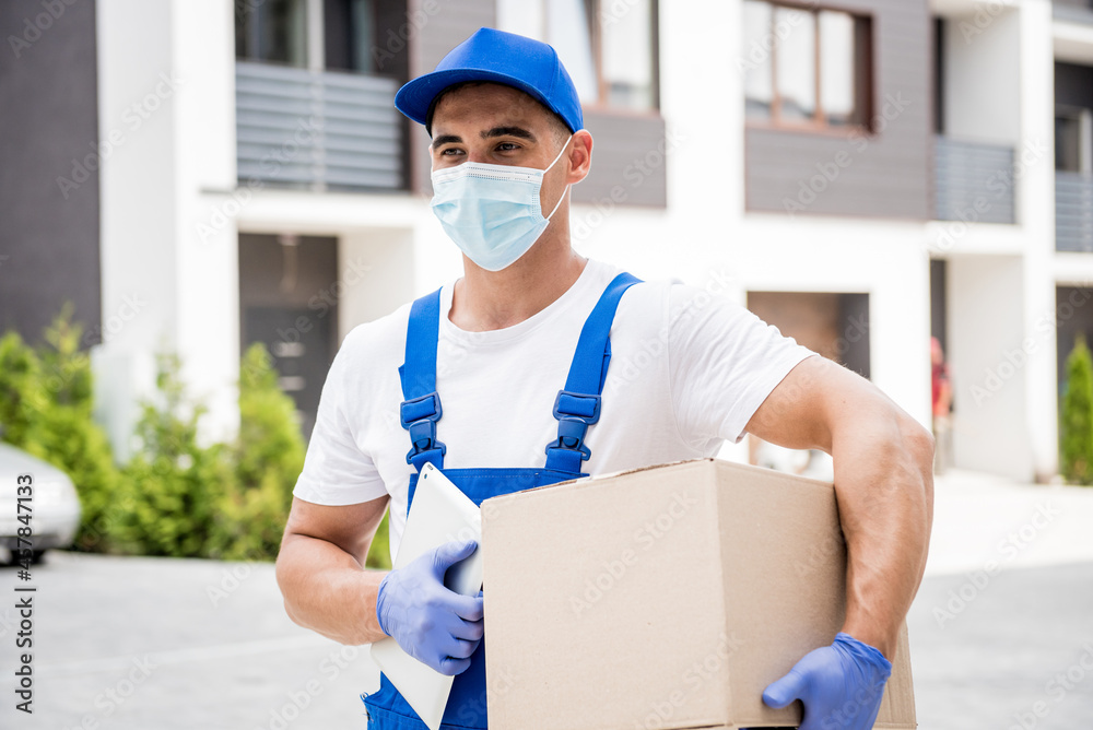 Young courier wearing a protective mask and gloves delivers goods during quarantine Young courier wearing a protective mask and gloves delivers goods during quarantine