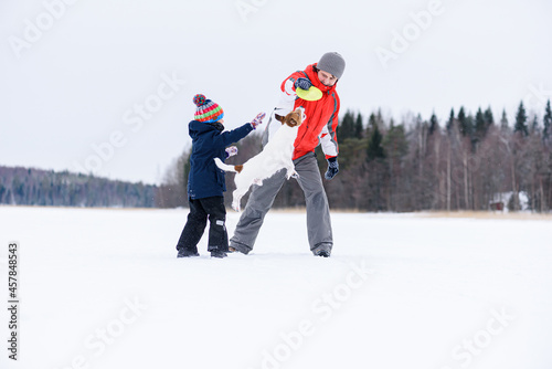 Farther and son playing together with dog outdoors in winter