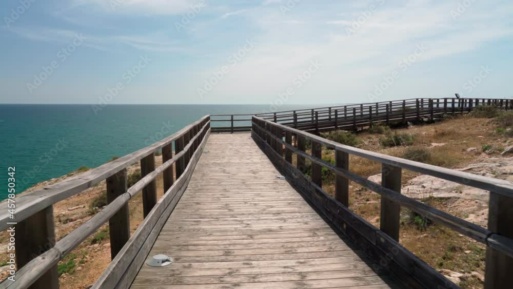Wonderful view of the Portuguese coast of Carvoeiro in summer, walking along the wooden paths. Overlooking the blue sea. Shooting in motion with a stabilizer. Wonderful view of the Portuguese coast of Carvoeiro in summer, walking along the wooden paths. Overlooking the blue sea. Shooting in motion with a stabilizer.