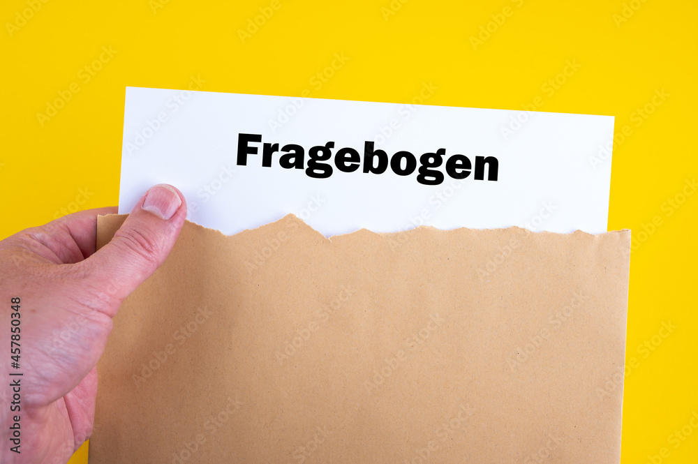 Eine Hand nimmt einen Fragebogen aus einem Briefumschlag Eine Hand nimmt einen Fragebogen aus einem Briefumschlag