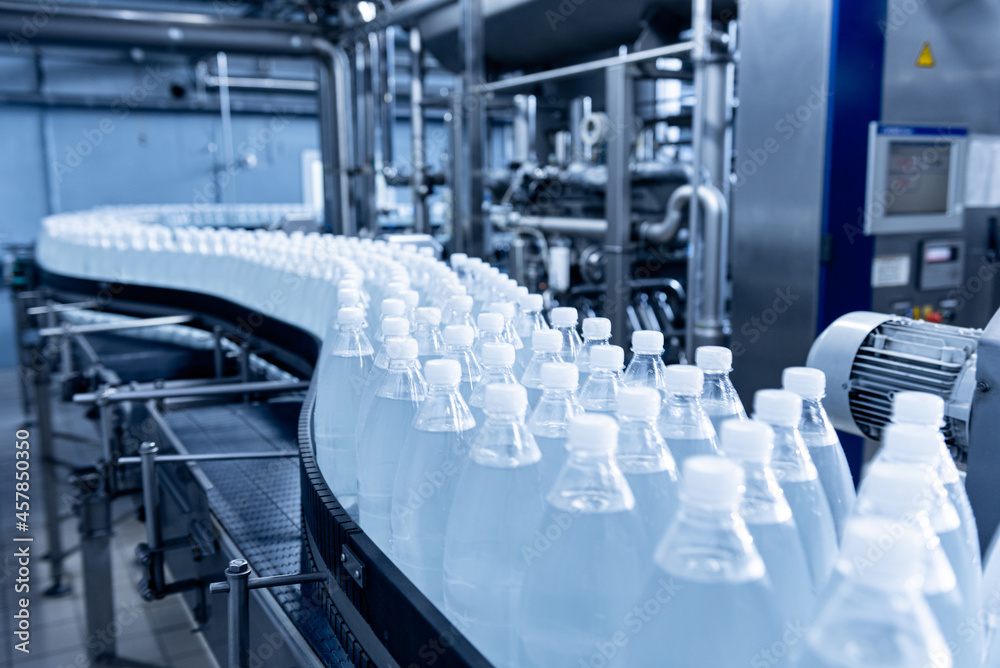 Conveyor belt with bottles of drinking water at a modern beverage plant. Conveyor belt with bottles of drinking water at a modern beverage plant.