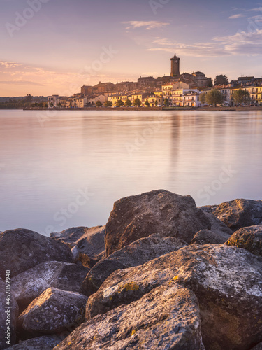 Foto view through stones and lake to city Marta on lake Bolsena in Italy in morning l