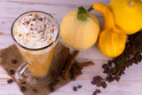 Pumpkin latte with spices and whipped cream on a white wood background. View from above.