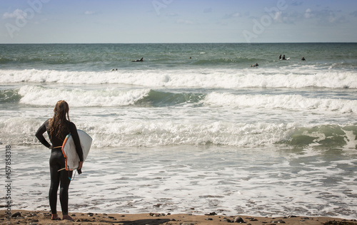 Black Rock Beach, Widemouth Bay in Bude Cornwall UK -  female surfer watching the surfers