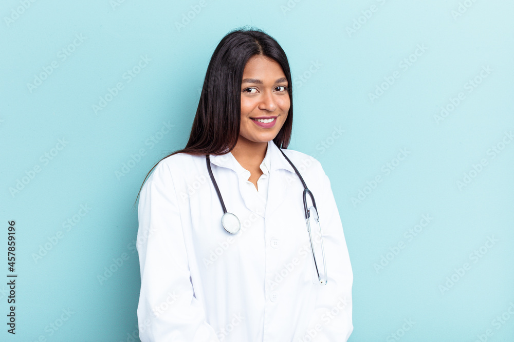 Young doctor Venezuelan woman isolated on blue background looks aside smiling, cheerful and pleasant. Young doctor Venezuelan woman isolated on blue background looks aside smiling, cheerful and pleasant.