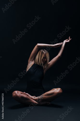 a forty-year-old woman in excellent physical shape with elastic muscles and healthy skin performs yoga exercises on a dark background. Studio photography. excellent health at forty.
