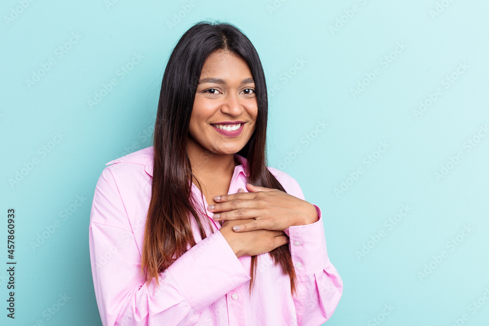Young Venezuelan woman isolated on blue background has friendly expression, pressing palm to chest. Love concept. Young Venezuelan woman isolated on blue background has friendly expression, pressing palm to chest. Love concept.