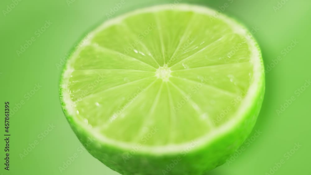The fresh limes are rotating slowly on bright green background. Concept of fruit vitamins and healthy food. Close up. The fresh limes are rotating slowly on bright green background. Concept of fruit vitamins and healthy food. Close up.