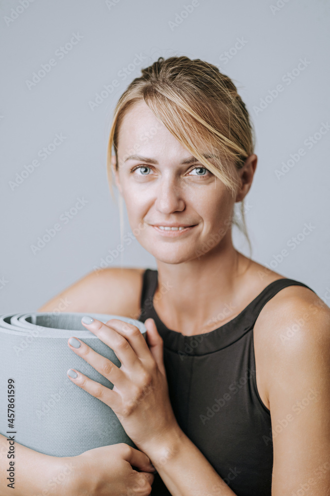 portrait of a young and energetic woman in her early forties with beautiful healthy skin and teeth. woman holding a sports mat portrait of a young and energetic woman in her early forties with beautiful healthy skin and teeth. woman holding a sports mat