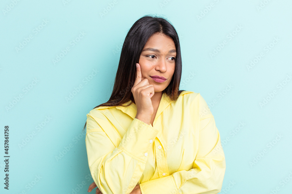Young Venezuelan woman isolated on blue background contemplating, planning a strategy, thinking about the way of a business.